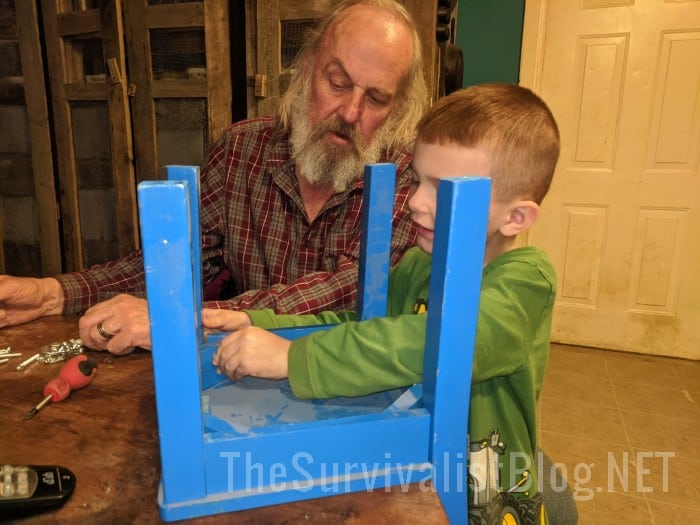 grandfather teaching newphew how to assemble a chair